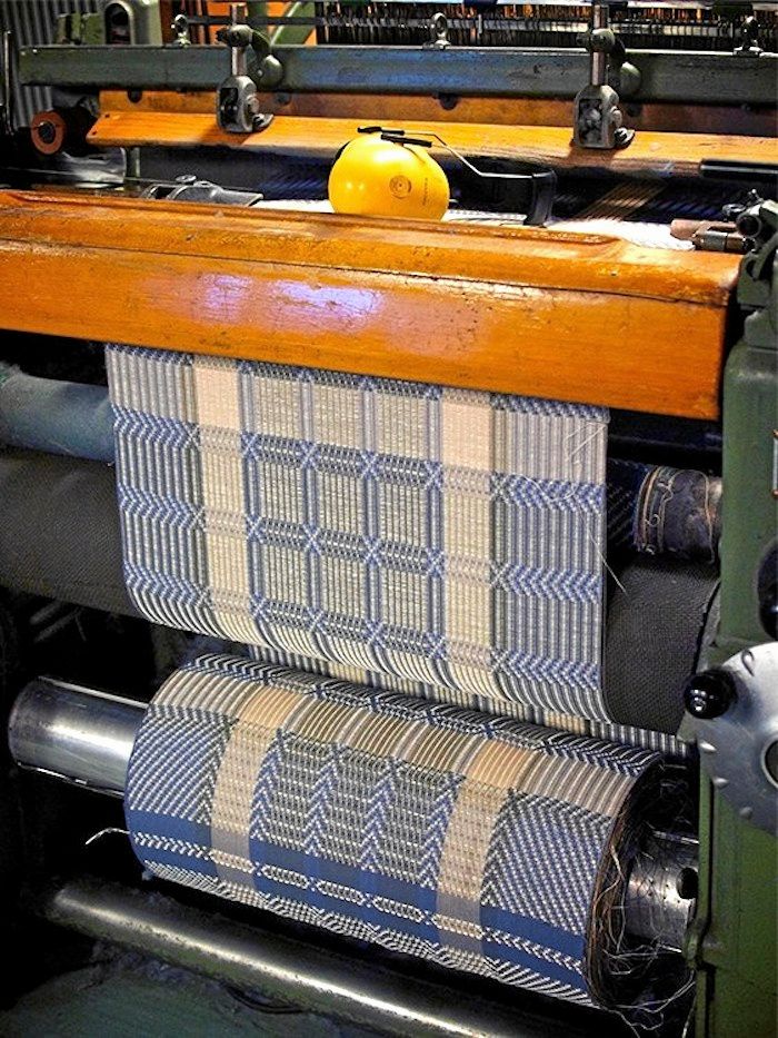 De hundra år gamla vävstolarna slamrar men väver tyg som är så lika handvävt som möjligt.