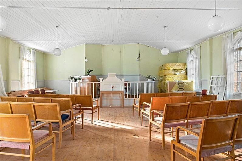 I kyrksalen står stolsrader och altare kvar. Fönstren har vackra detaljer.