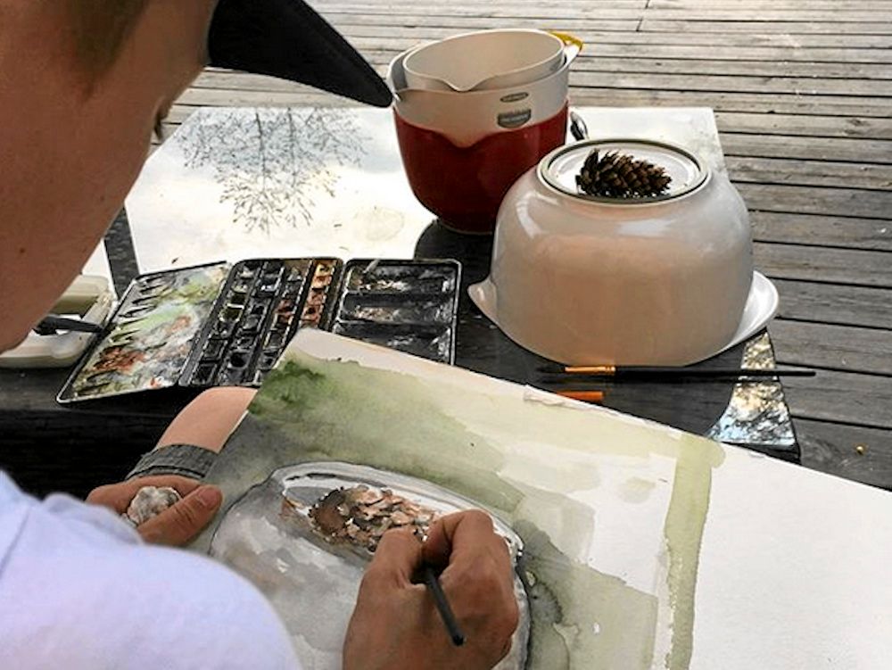 Maxi koncentrerat böjd över en akvarellmålning.