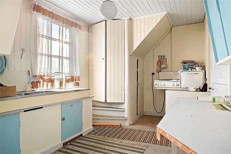 Köket har babyblå luckor och lodrät vit väggpanel.