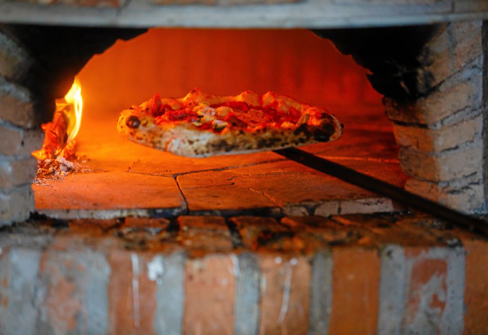 Glödhett i deras egenbyggda vedugn där neapolitanska pizzor gräddas, gjorda av råvaror från Varaslätten.
