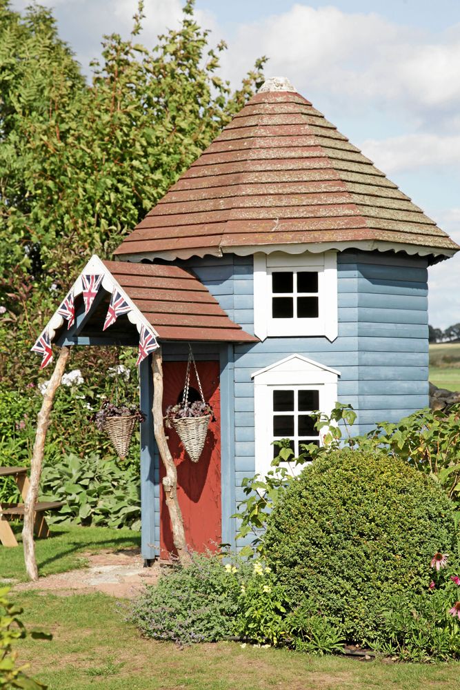 Blått blickfång och förråd vid paradrabattens ände i Den Engelska Trädgården, Kivik. Lägg märke till att fönstren är svartmålade, men visst ser det ut som glas.
