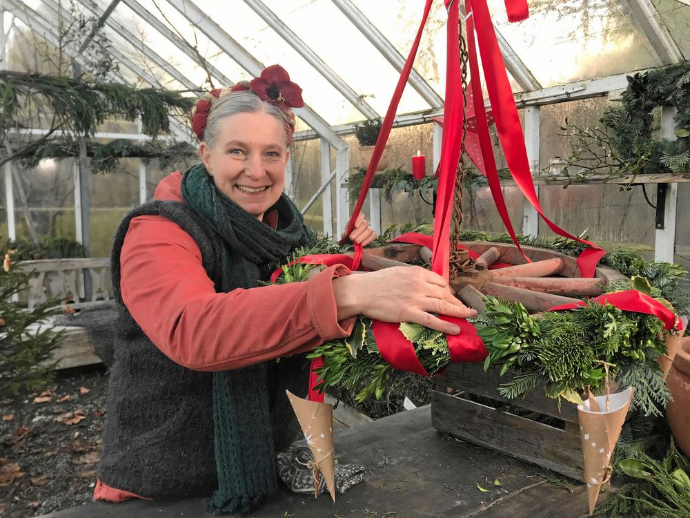 Marie binder en fin krans med granris och lingonris från skogen dekorerad med pappersstrutar och röda sidenband.