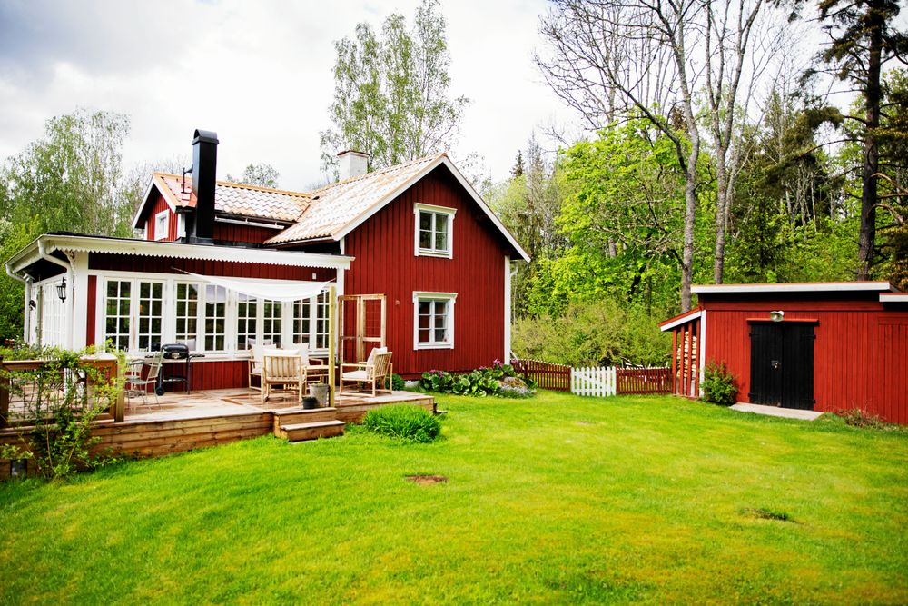 Torpet med sin tillbyggda glasveranda "väggar" av stora spröjsade fönster utanför löper rejäla trädäck med plats för flera sittgrupper.