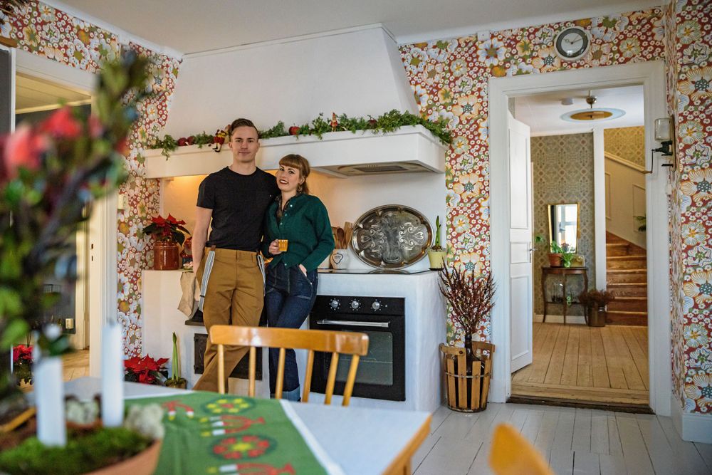 Grangirland på spiselkransen med små tomtar och fåglar ger julstämning i köket, tillsammans med julduk och julblommor.