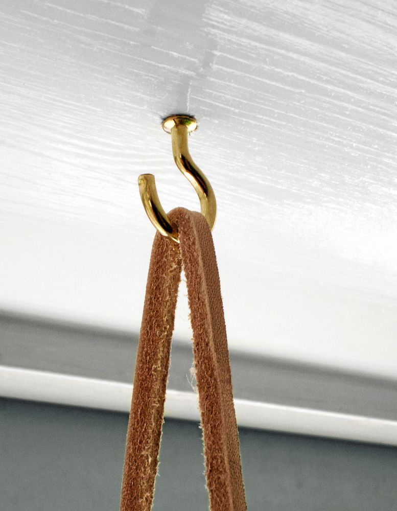 Två krokar i fönstersmygens "tak" får hyllan att hänga i fönstret.