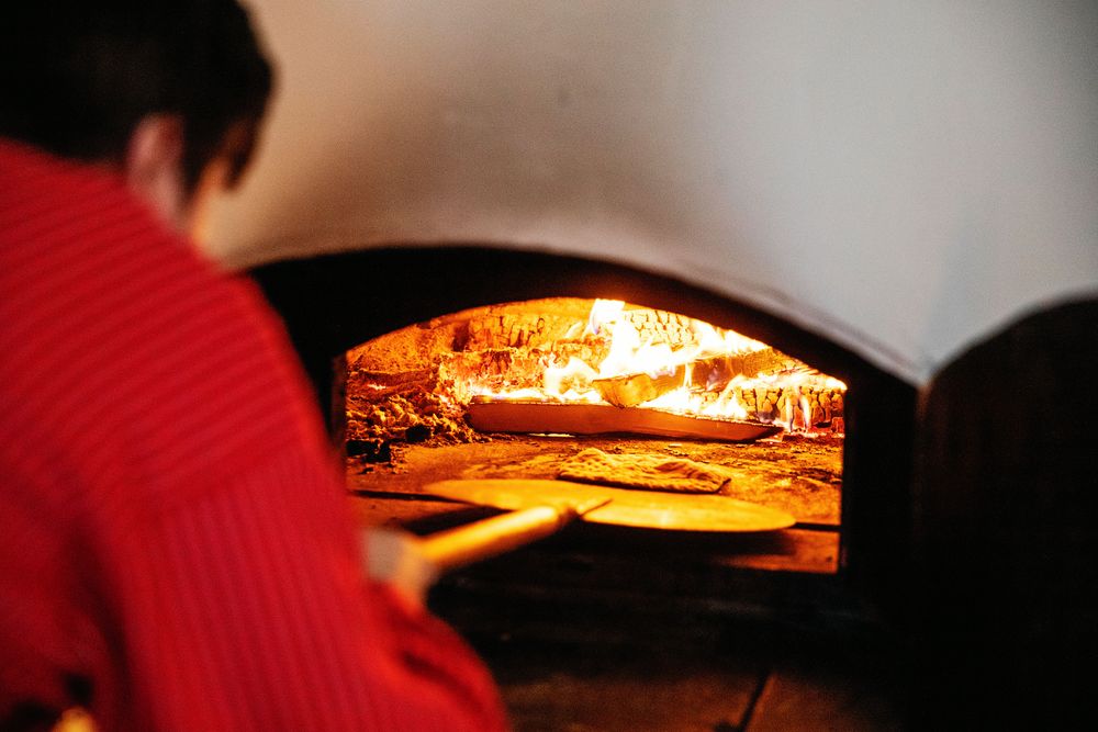 Joar skjutsar in tunnbröd för gräddning i den heta, vedeldade bakugnen.