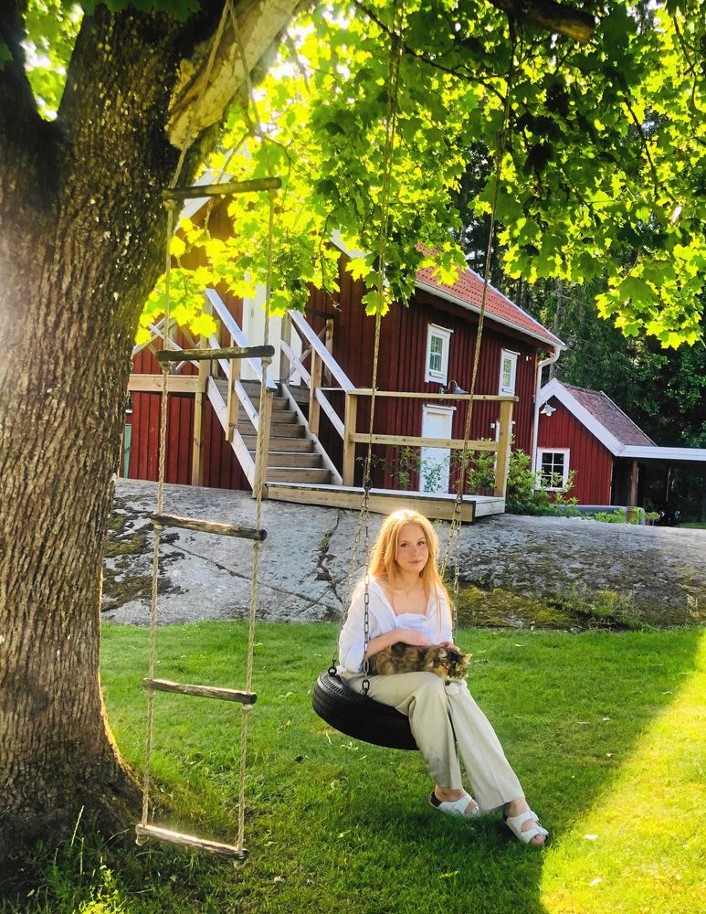 Den äldsta dottern Lisa kopplar av i trädets skugga i sin barndoms gunga med katten Morran