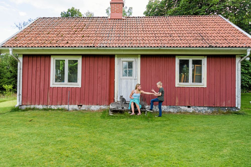 Anja och Anton framför den lilla stugan som är en av de få gamla byggnader som gick att bevara.