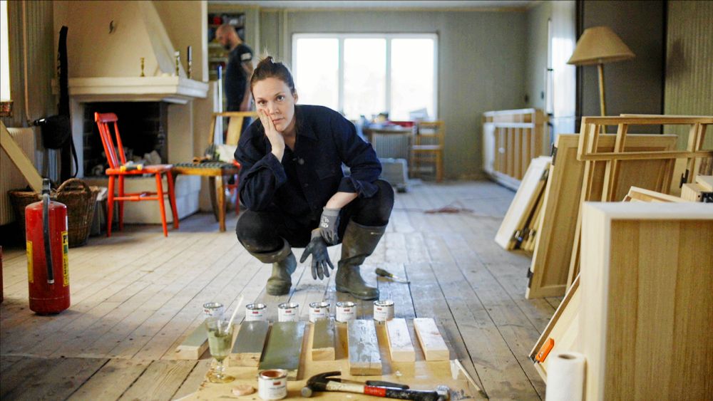 Det tog lite tid innan Brita bestämde färg till köket. Här sitter hon på golvet i vardagsrummet där det gamla trägolvet har tagits fram.