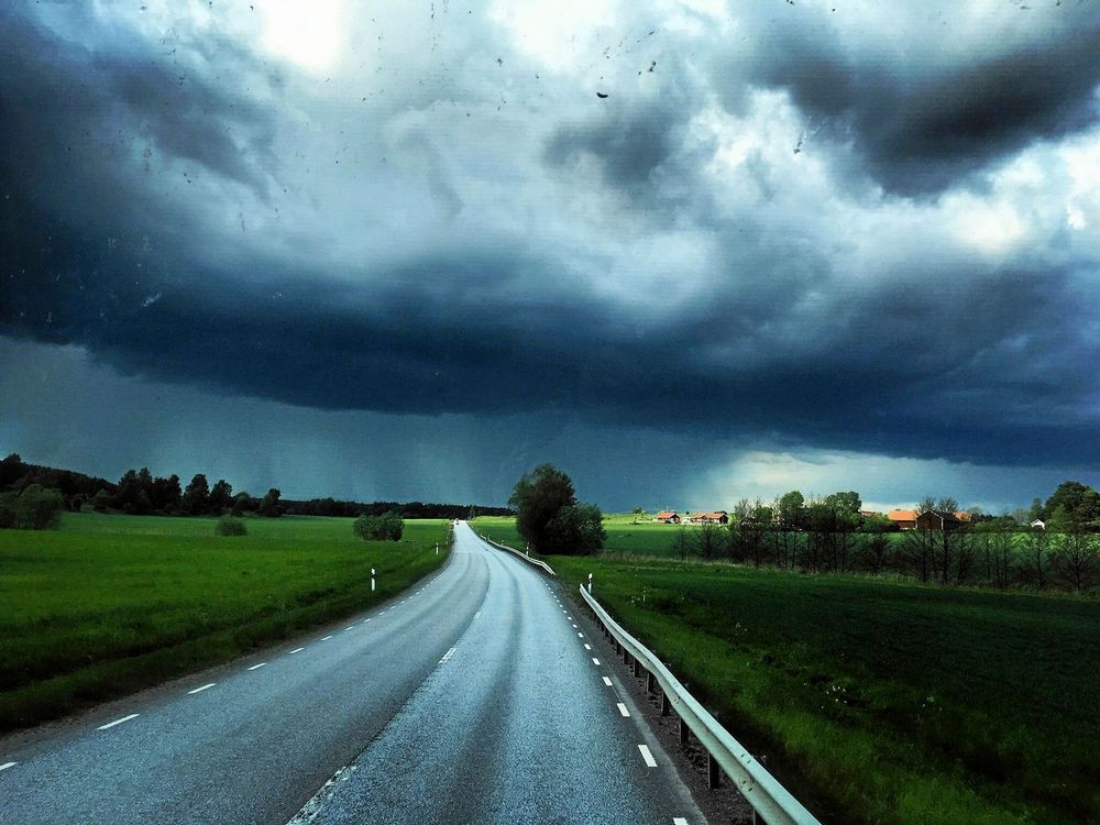 PLATS 6-10. Therese Åström i Stockholm fotograferade en hotfull molnbank över en typisk svensk landsväg. Regnet faller och samtidigt lyser solen.