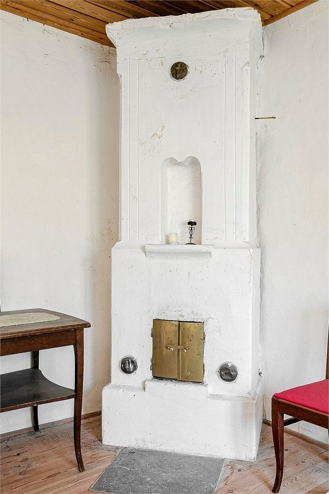 Vitmålad eldstad i boningshuset.