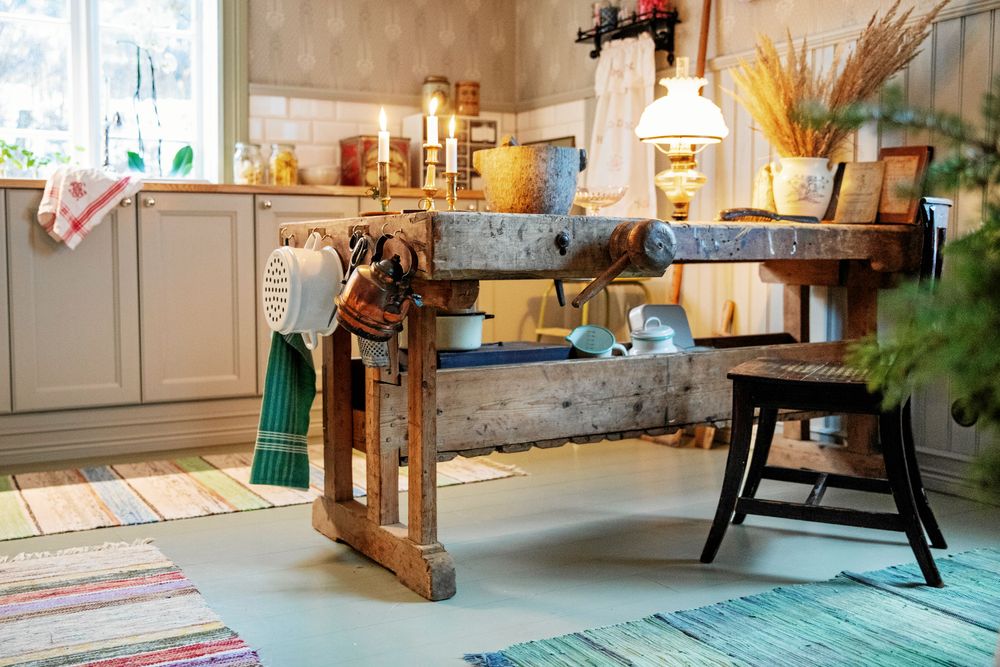 Det grova träet i den gamla snickarbänken ger fin kontrast mot de levande ljusen och det torkade gräset.