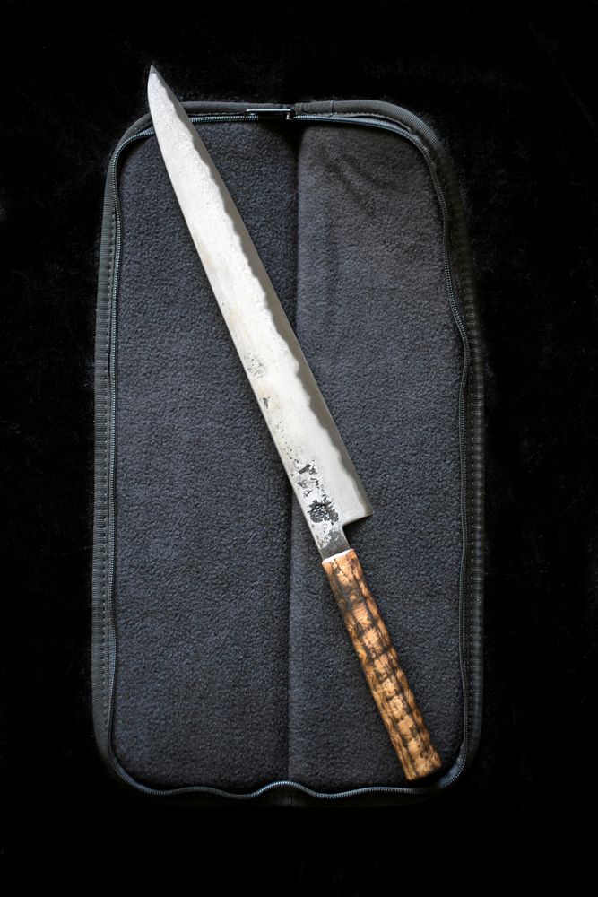 Kniv med japanskt sanmaiblad: tre lager härdat kärnstål i mitten och med mjukare järn på sidorna. Handtag i bränd ask.