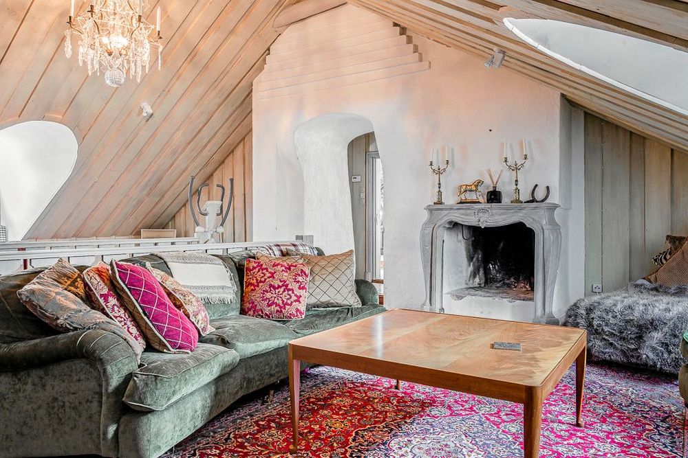 På övervåningen är ett stort allrum med öppen spis och de timrade takåsarna synliga som ger ett trivsamt intryck.