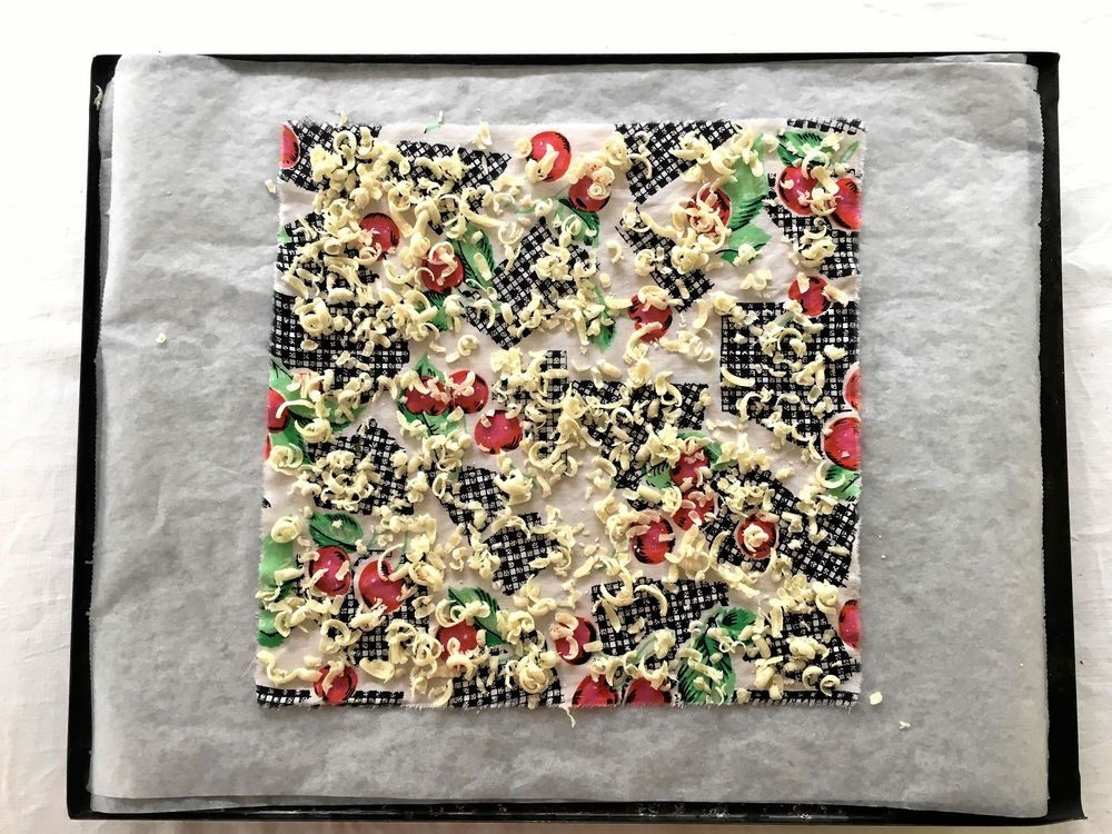 Smulor av bivax läggs ovanpå tyget.