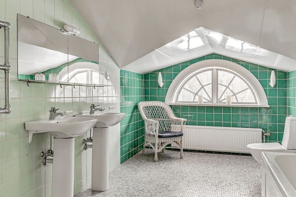 Badrummet har kaklade väggar och mosaikgolv och ett vackert halvmåneformat fönster att se ut över infarten till herrgården.