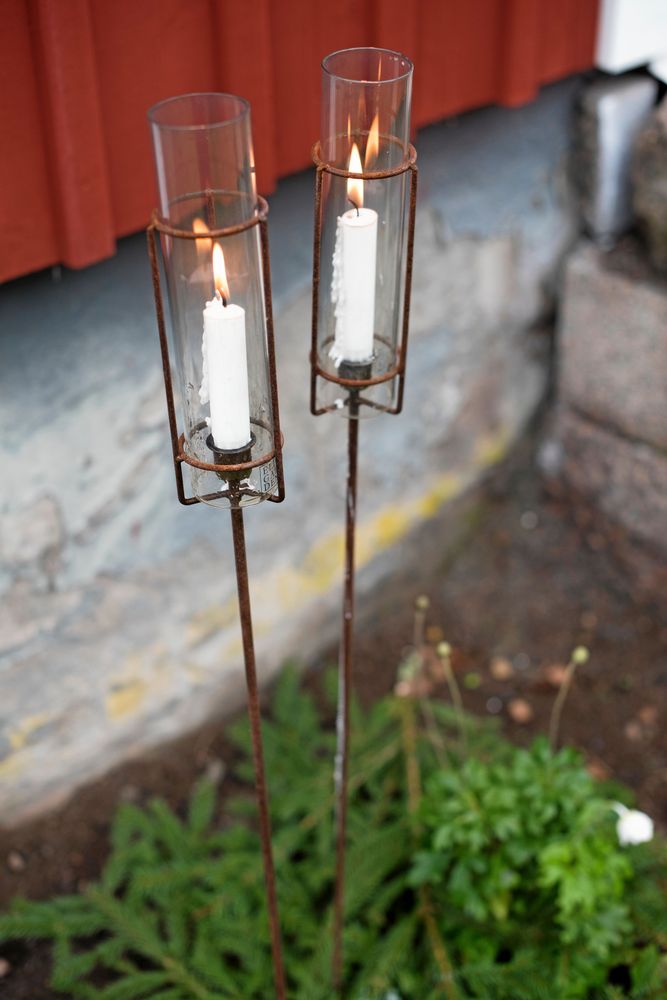 Vackra ljushållare av glas i hållare av fint rostig järn sprider ljus utomhus.