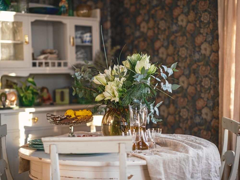 En vas med en generös bukett av vita amaryllis på matsalsbordet, som är köpt på auktion, liksom vitrinskåpet bakom.