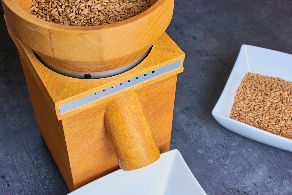 En liten kvarn för hemmabruk mal mjölet på köksbänken.