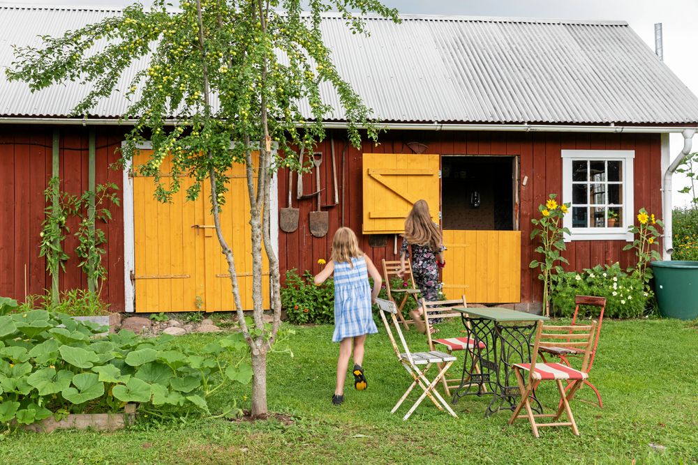 Döttrarna Maj-Britt och Karla vid torpet ombyggda lagård. Bakom halvdörrarna finns nu en snickarbod och i andra änden vedbod och utedass.