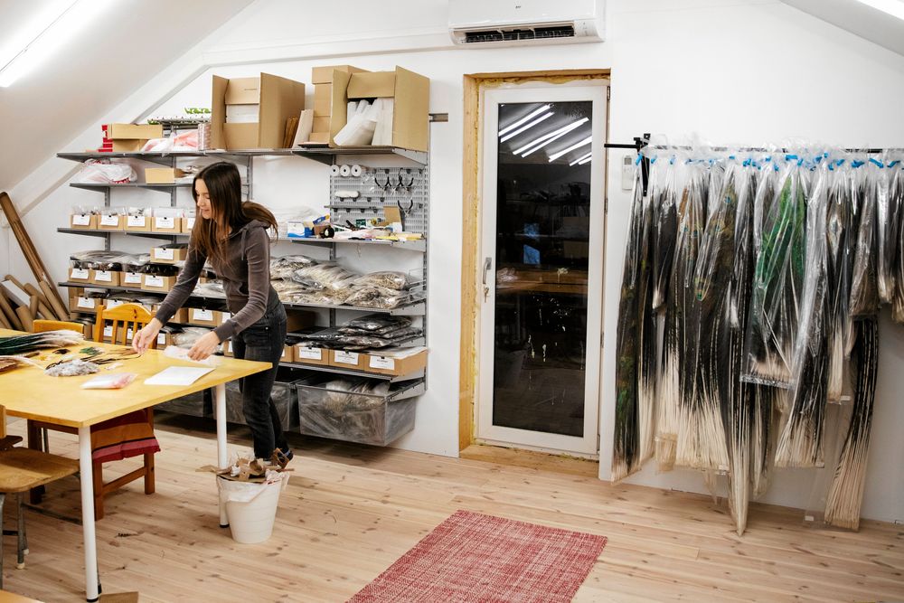 I webbutiken packar Therese fjädrarna. På klädställningen hänger de långa stjärtfjädrarna.