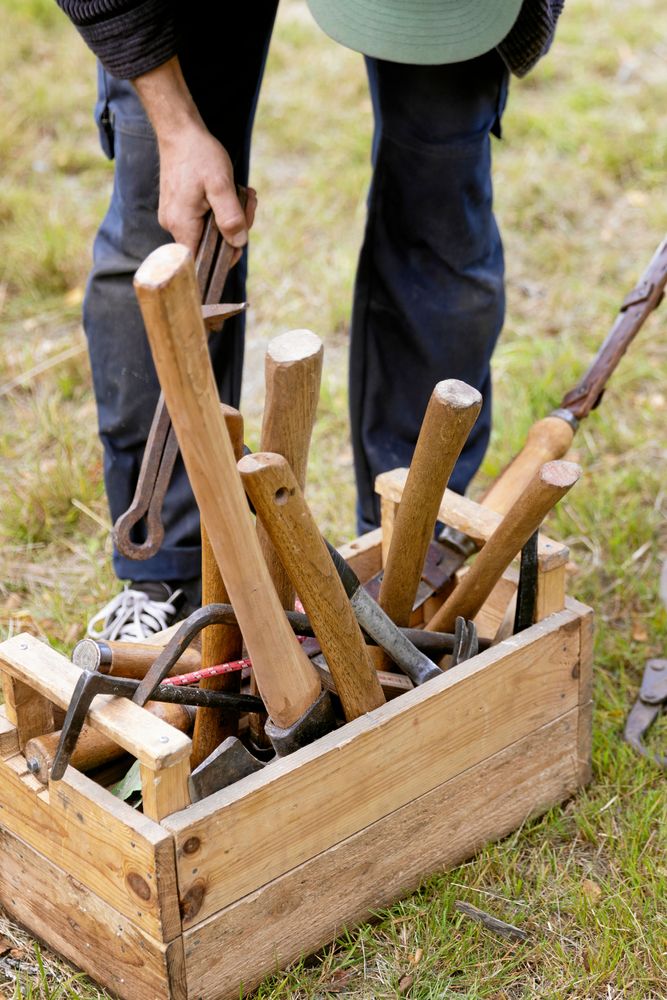 En låda full med en timmermans viktigaste verktyg, främst olika sorters yxor.