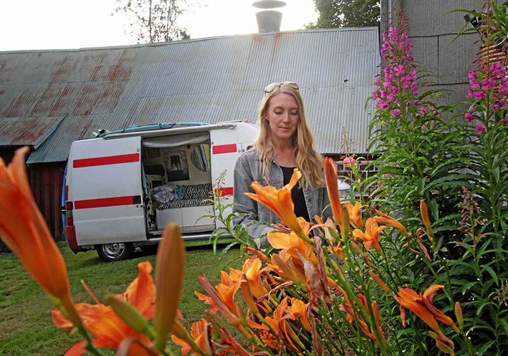 Emilia framför husbilen, som inretts med säng och möbler.