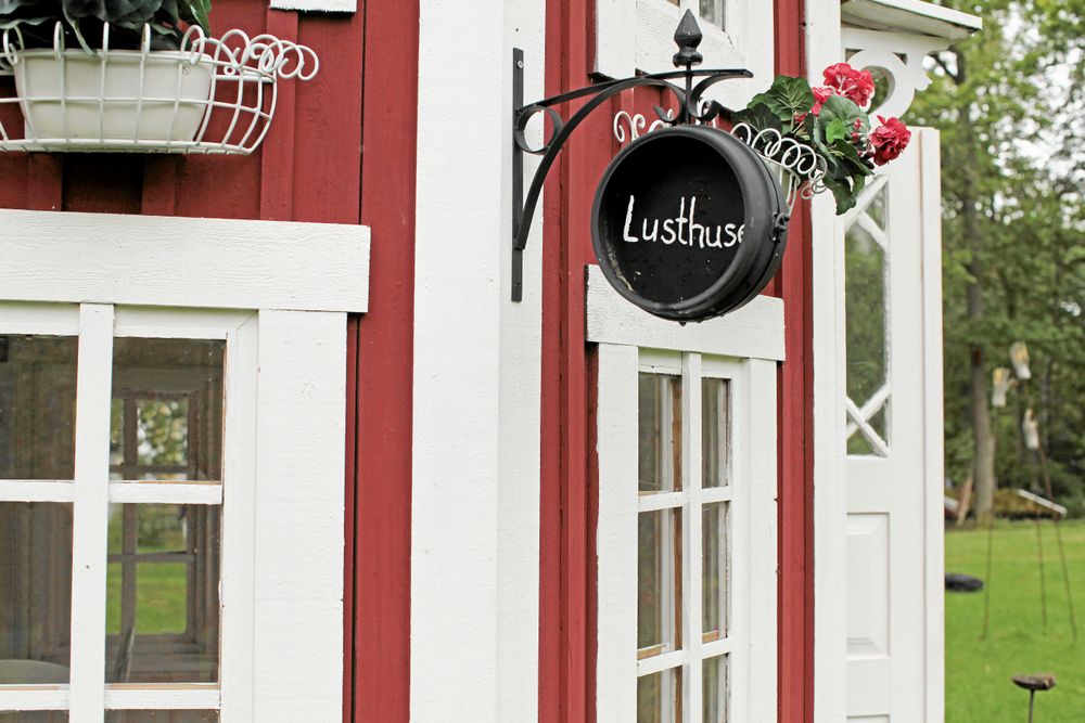 Lusthuset är köpt som monteringssats och sen fått personliga detaljer som skylt och blomlådor.