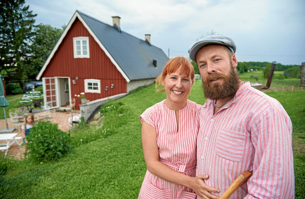Stolta bakstuesittare Lella och David Ernstedt framför sitt hus med de tillbyggda köksdelen närmast där skafferiet ligger mot backen och därför svalt.