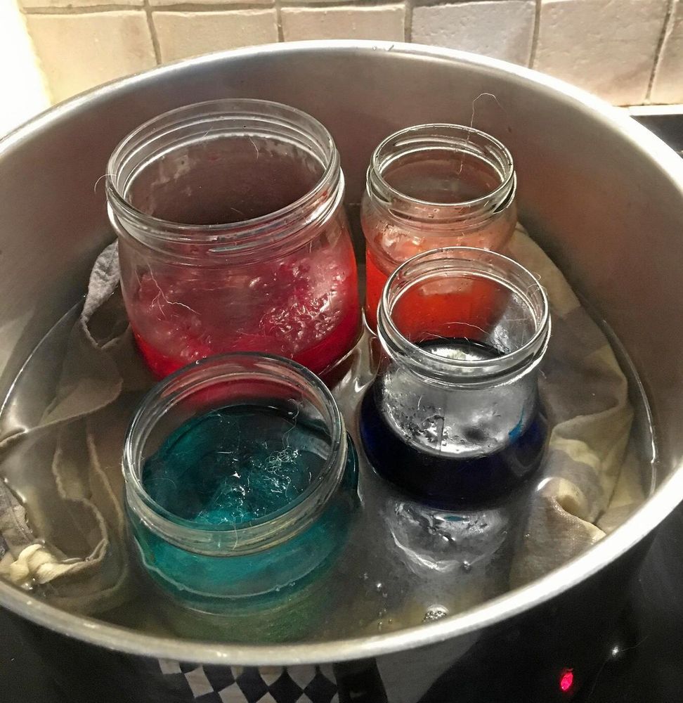 Burkar på handduk fulla med ull och färg. Bubblande experiment blev färgad ull till påskriset.