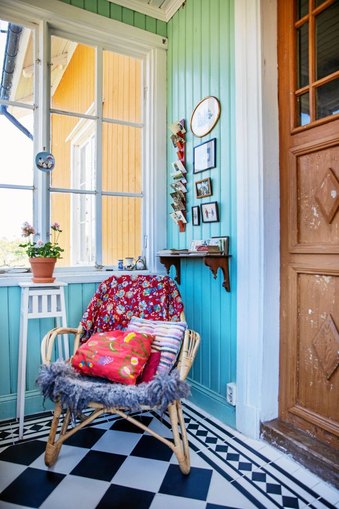 Den turkosa färgen i farstuns väggpanel matchar det svartvitrutiga golvet.