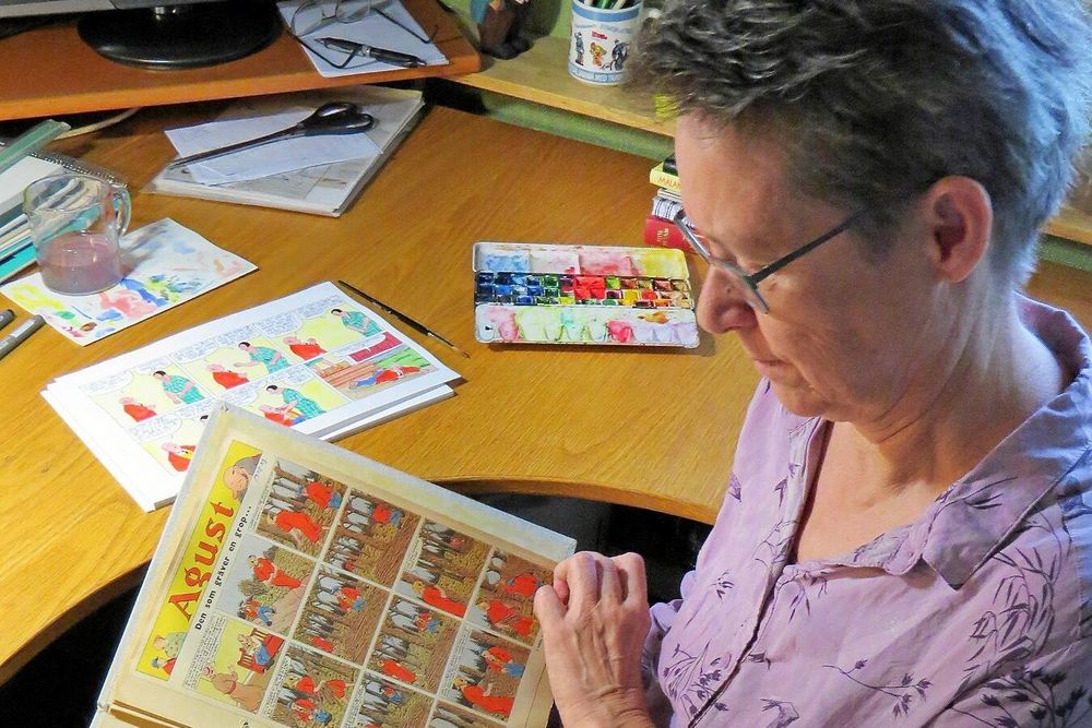 Bia Melin bläddrar i ett seriealbum från 1940-talet, då det var farfar Elov Persson som tecknade serien.