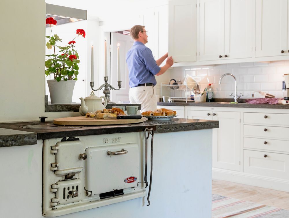 Pontus ordnar fram fika och kaffekoppar i det stora herrgårdsköket där vedspisen bevarats.