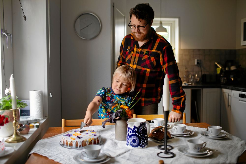 Agnar skär upp en bit av den nybakta kakan under Fredriks övreinseende.