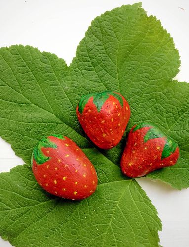 Med stenar målade som jordgubbar kan du få ha de riktiga i fred. En trast kommer hoppande i jordgubbslandet, på väg att hacka i sig en saftig gubbe.